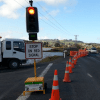 Cones placed along the road, a stoplight, and a mix of trucks and cars on the road